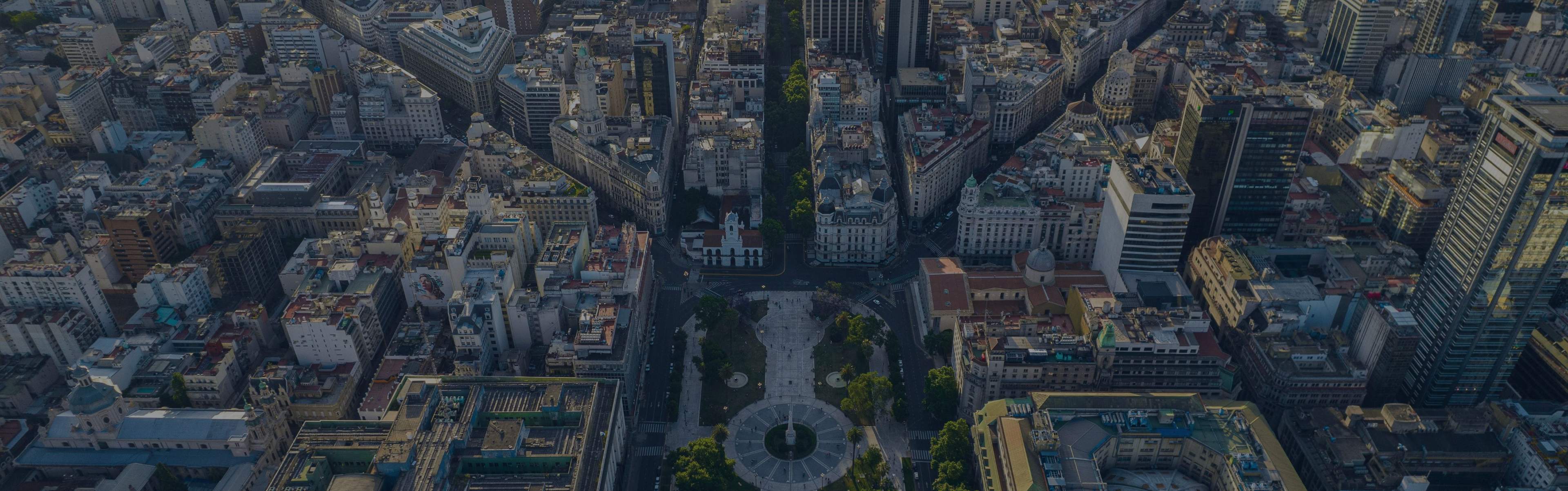 Aerial view of a bustling city with a circular park and numerous tall buildings.