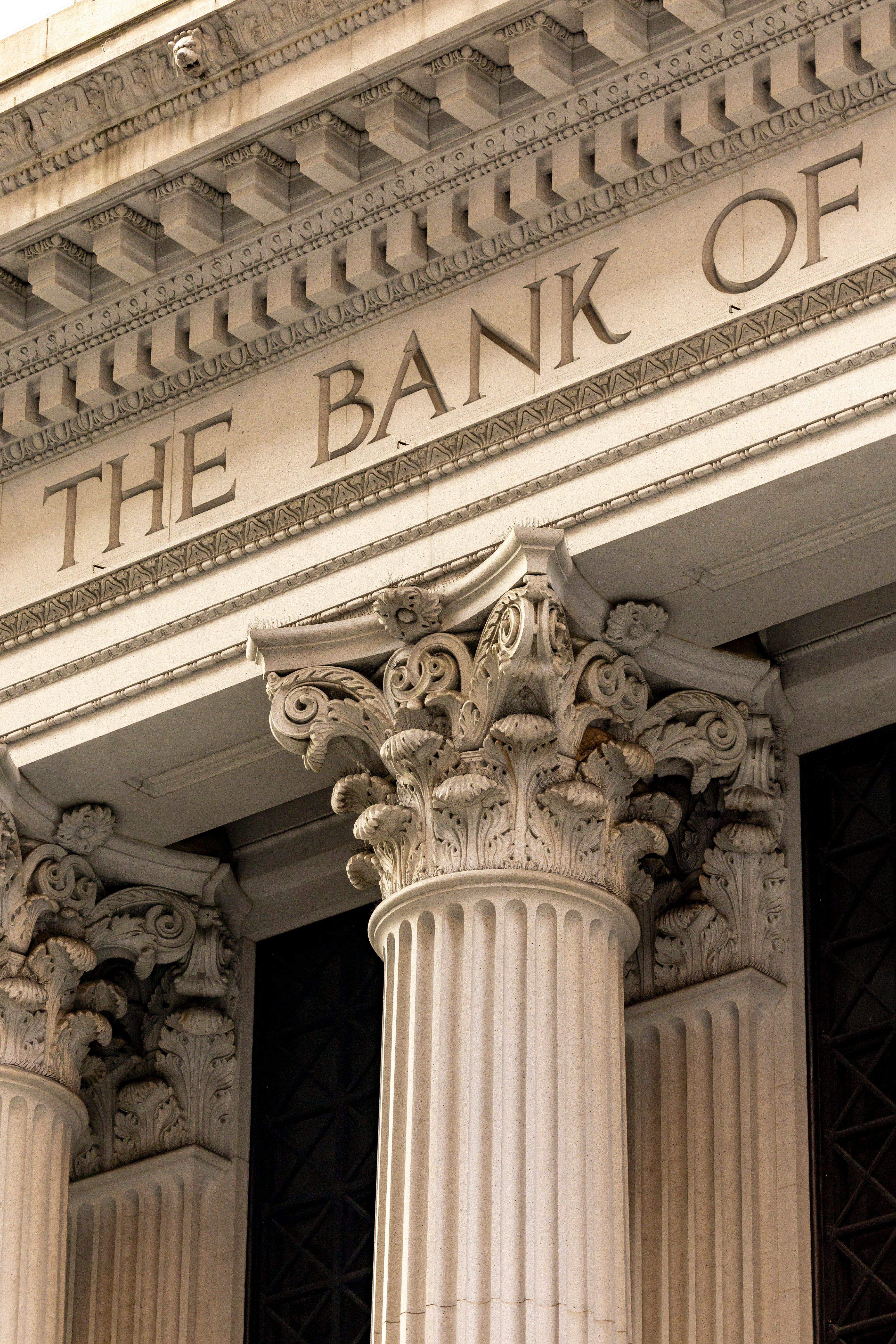 Detail of a classical building facade with "THE BANK OF" inscribed above ornate Corinthian columns.