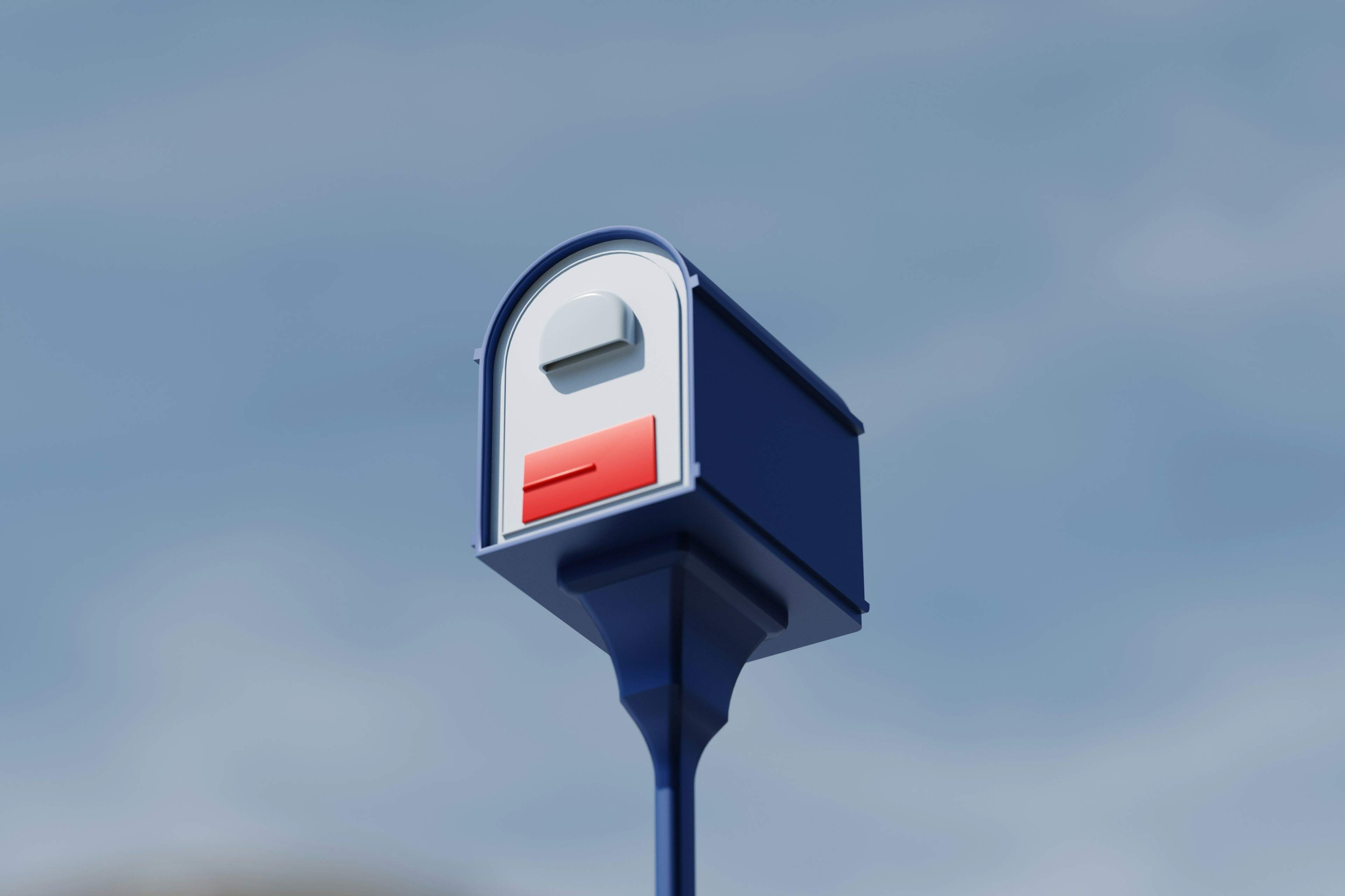A blue mailbox with a red flag down against a clear sky, indicating mail service.