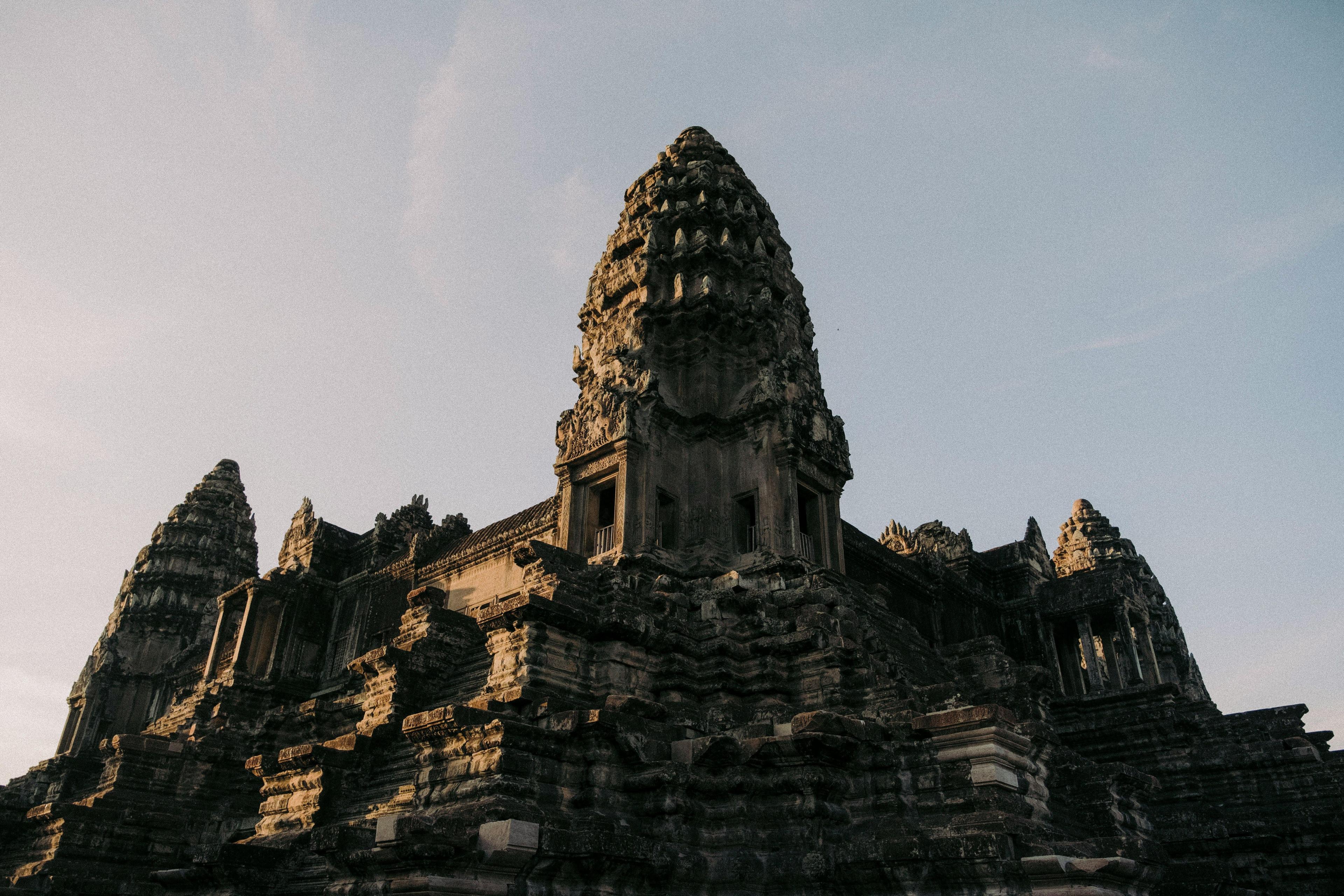 Ancient stone temple with multiple tiered towers reaching skyward under a clear sky.