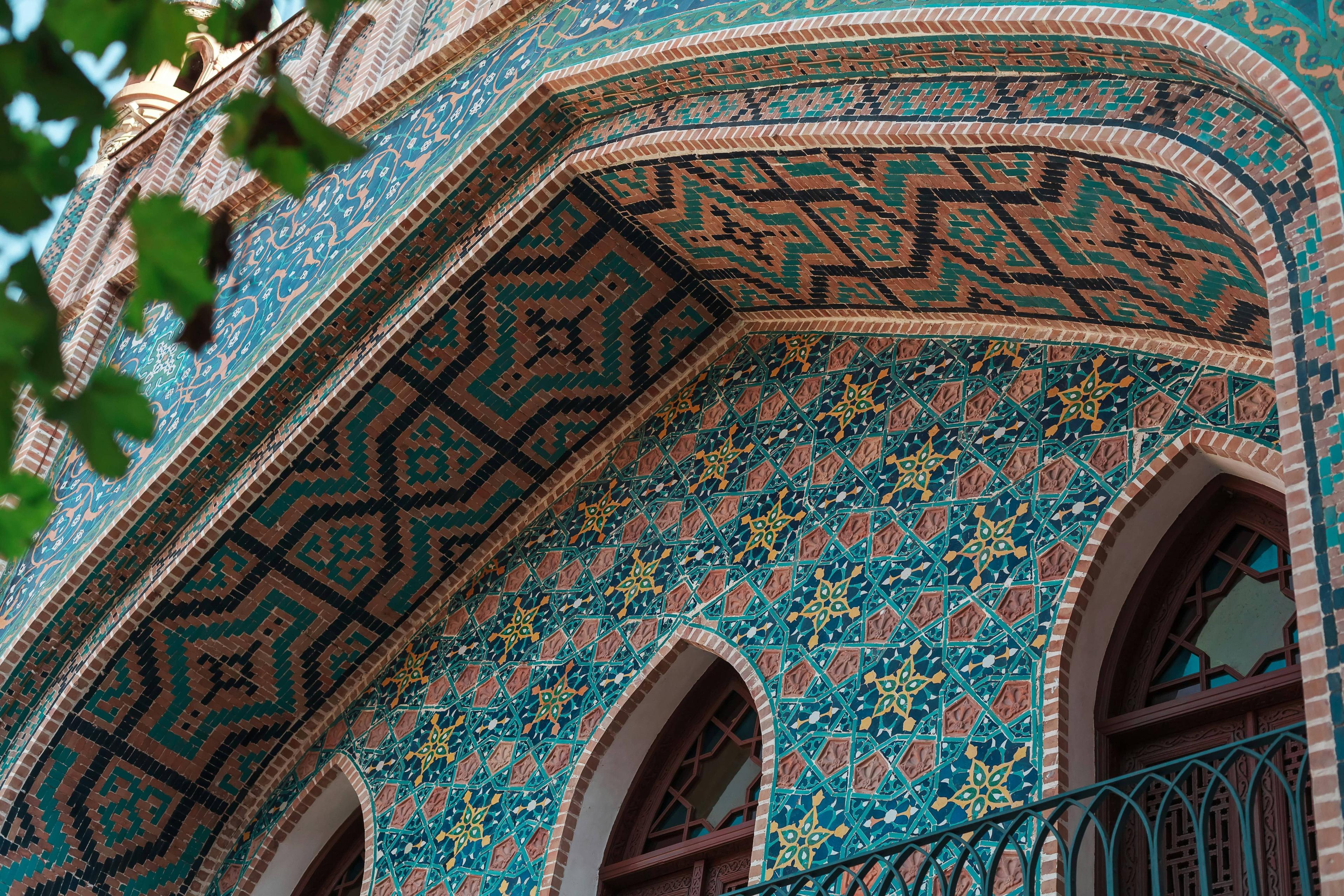 Building facade covered in vibrant blue, green, and orange geometric mosaic tiles.