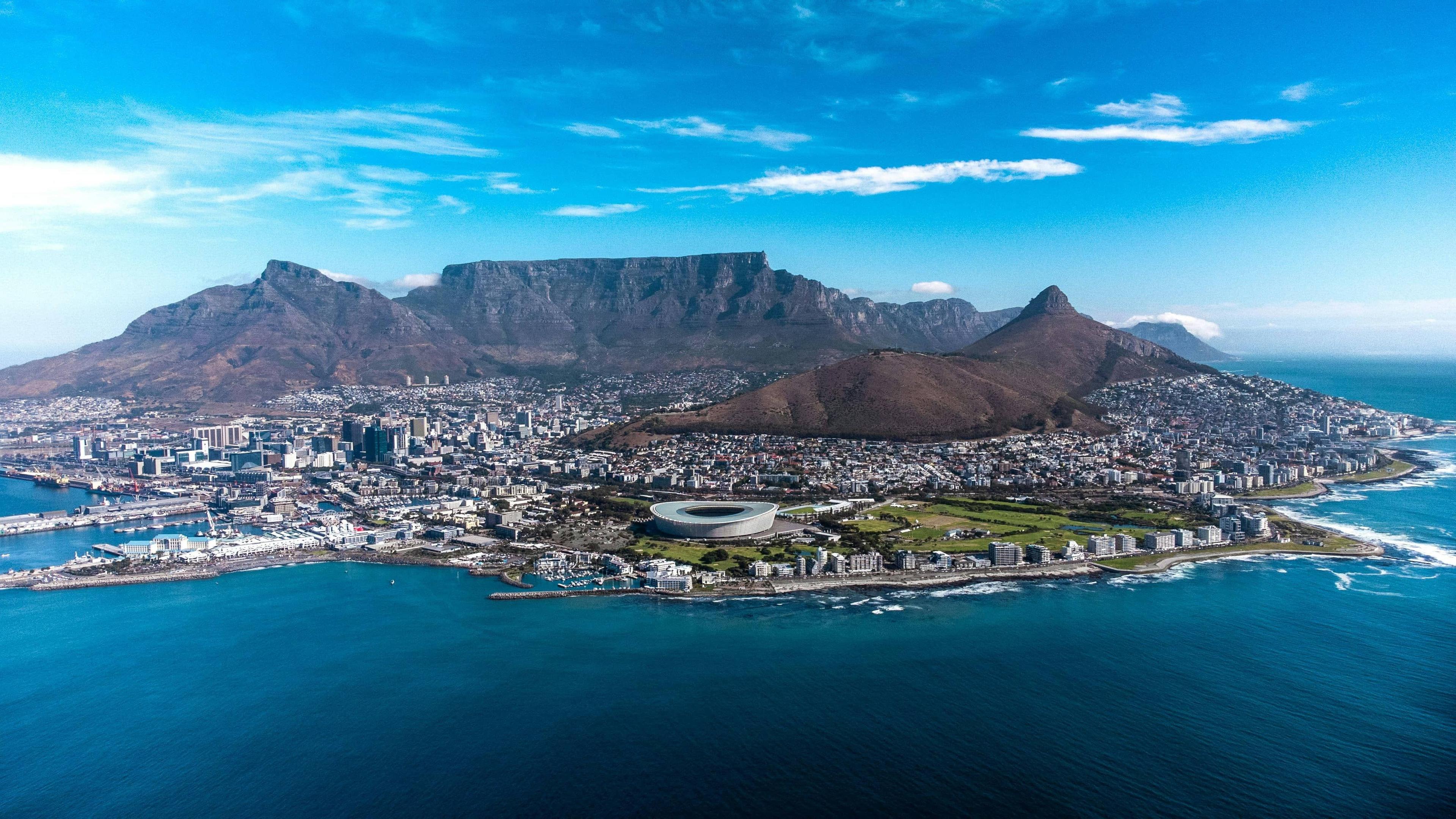 Aerial view of Cape Town city, stadium, and harbor with Table Mountain in background.