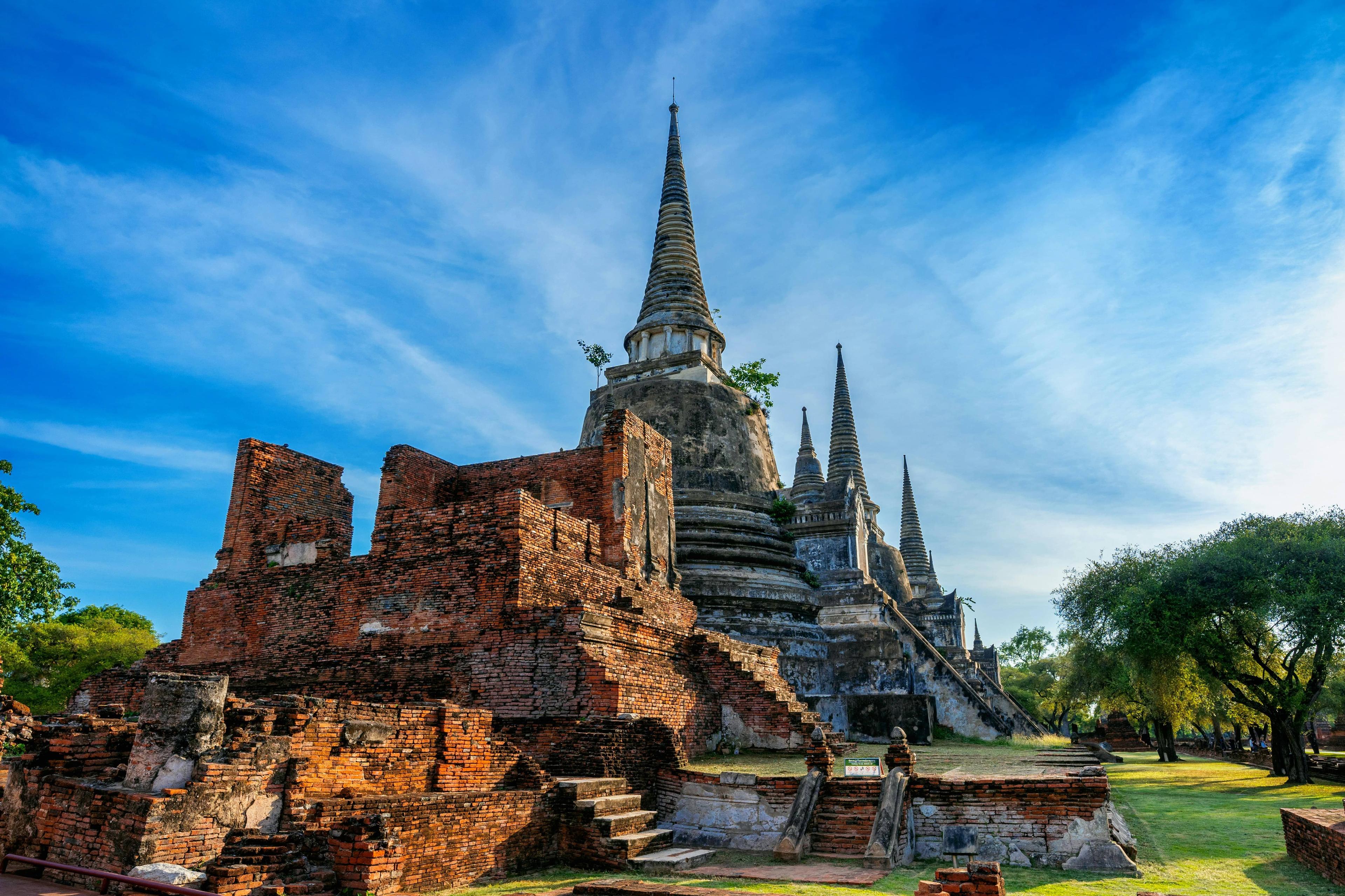 Ancient red brick temple ruins with towering, pointed stupas under a clear blue sky.