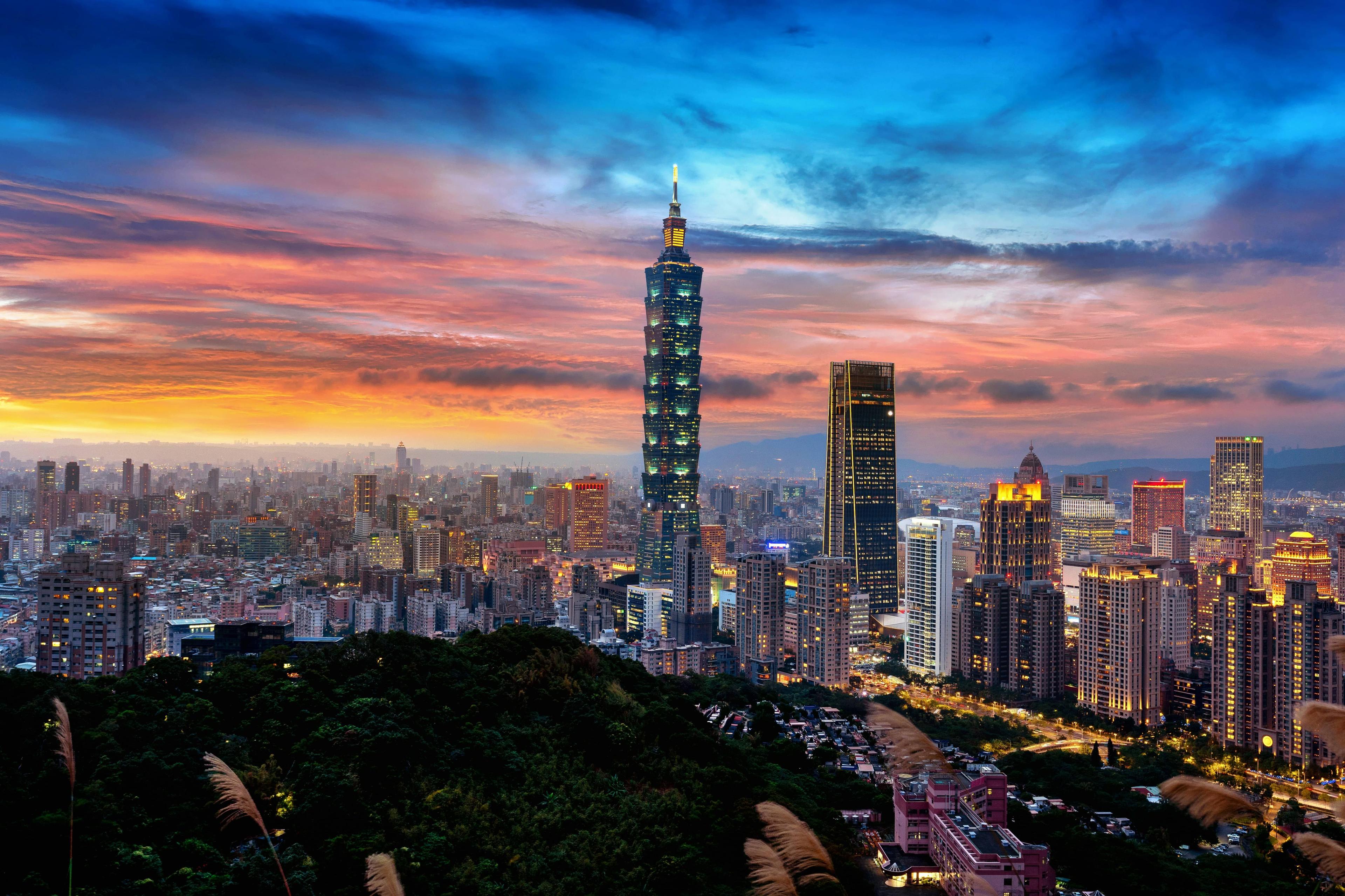 Panoramic view of Taipei 101 and city skyline against a colorful sunset.