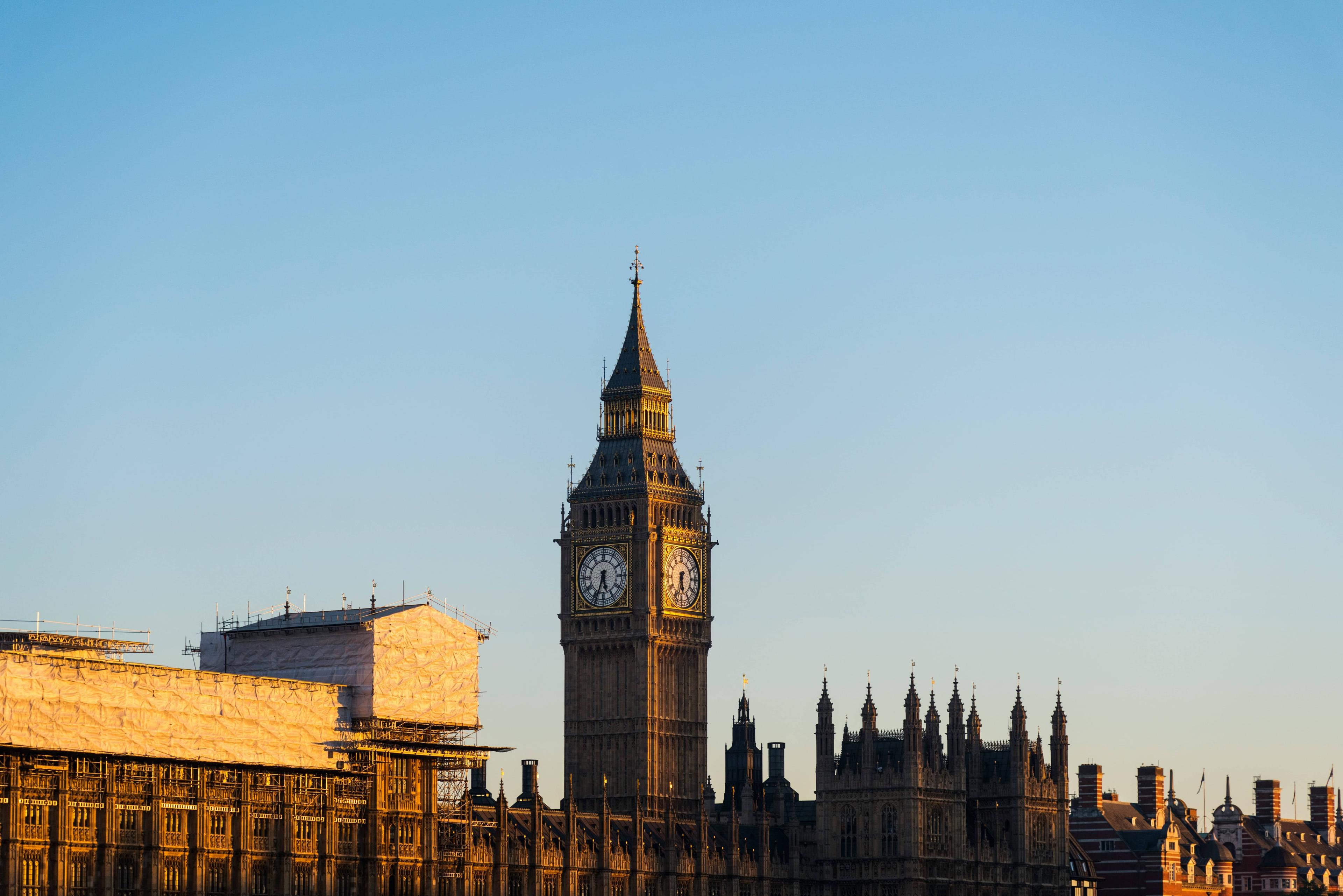Iconic Big Ben clock tower and Houses of Parliament against a clear blue London sky.