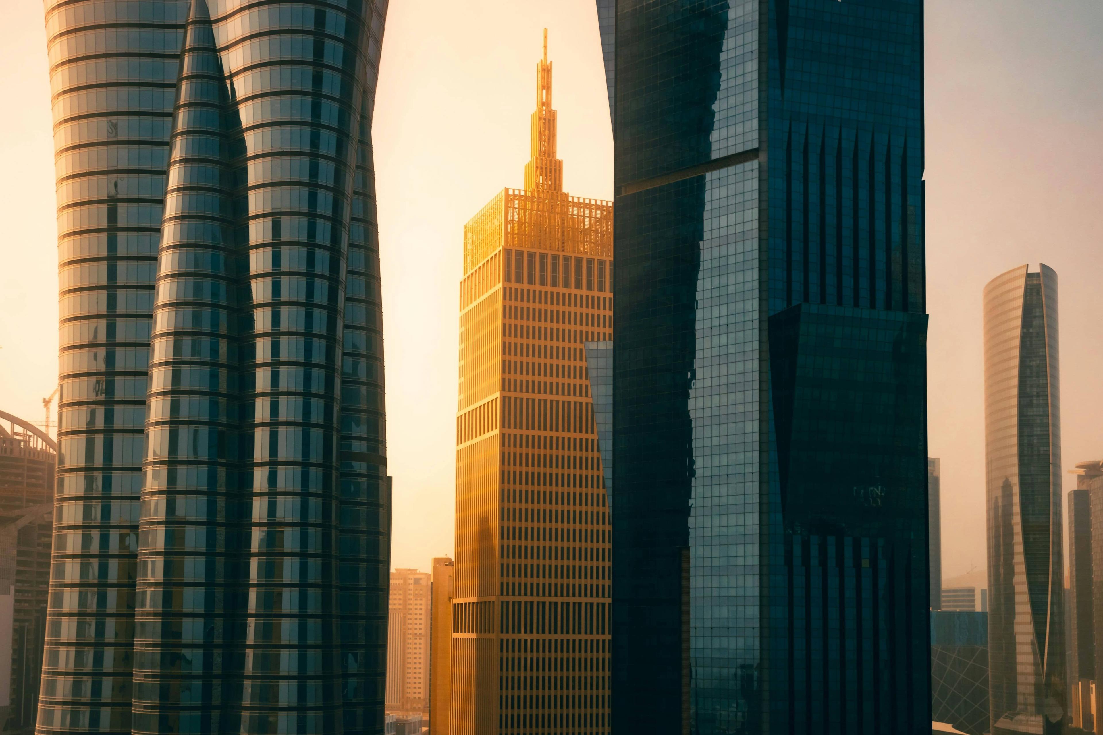 Modern skyscrapers with unique architecture bathed in golden hour sunlight.