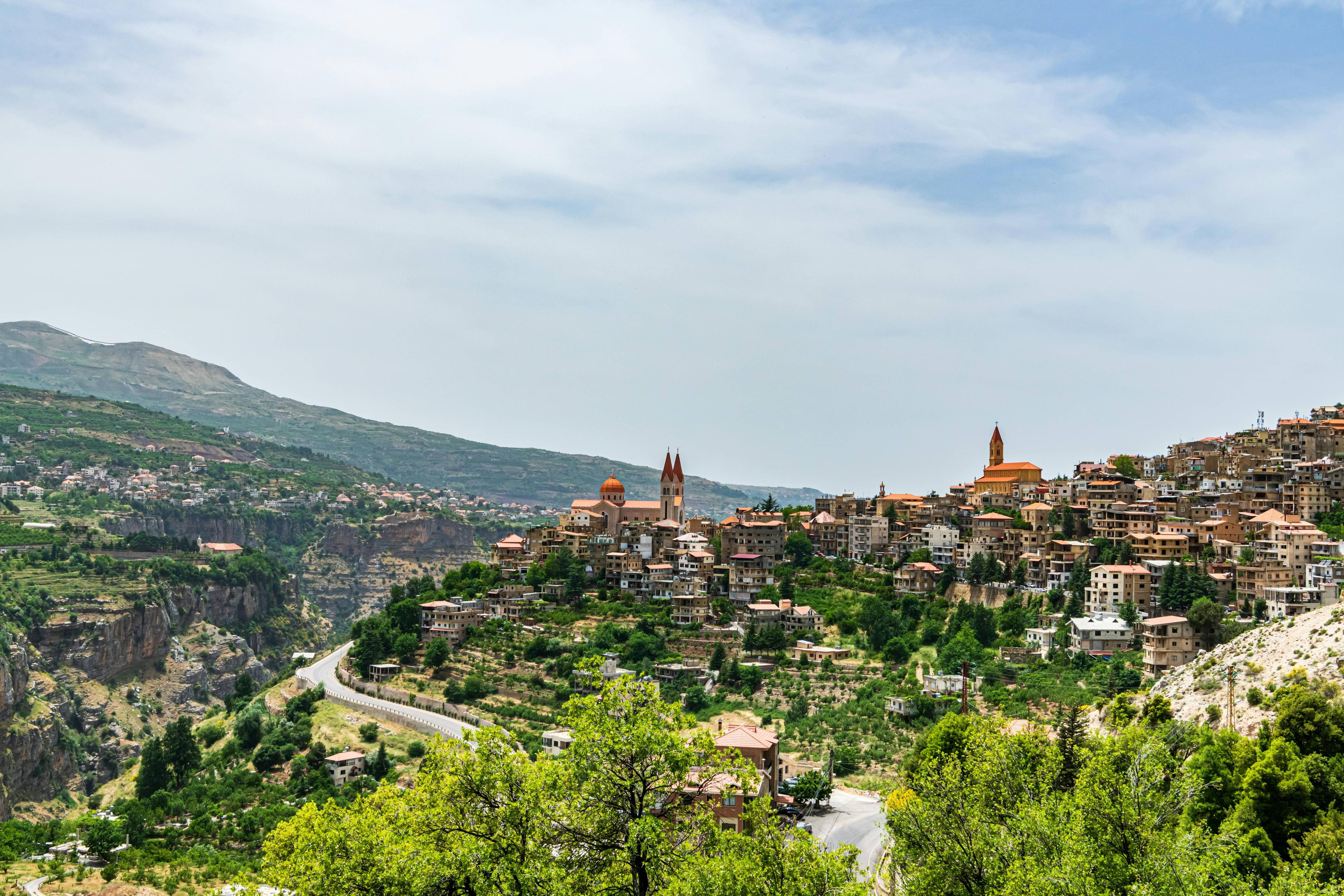 Historic village on a green hillside overlooking a winding road in a majestic mountain valley.