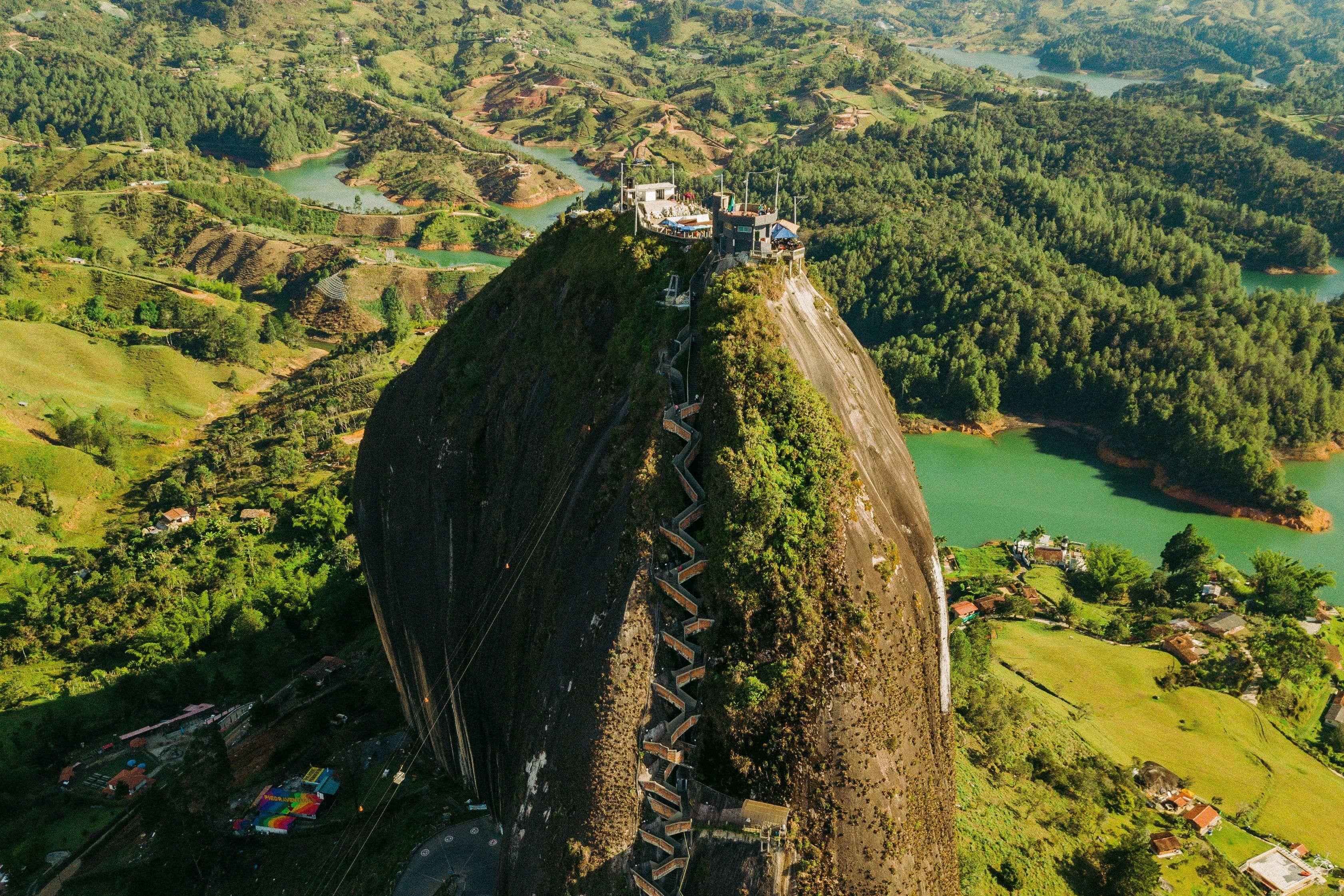 El Peñol rock with stairs, surrounded by green hills and a turquoise reservoir in Colombia.
