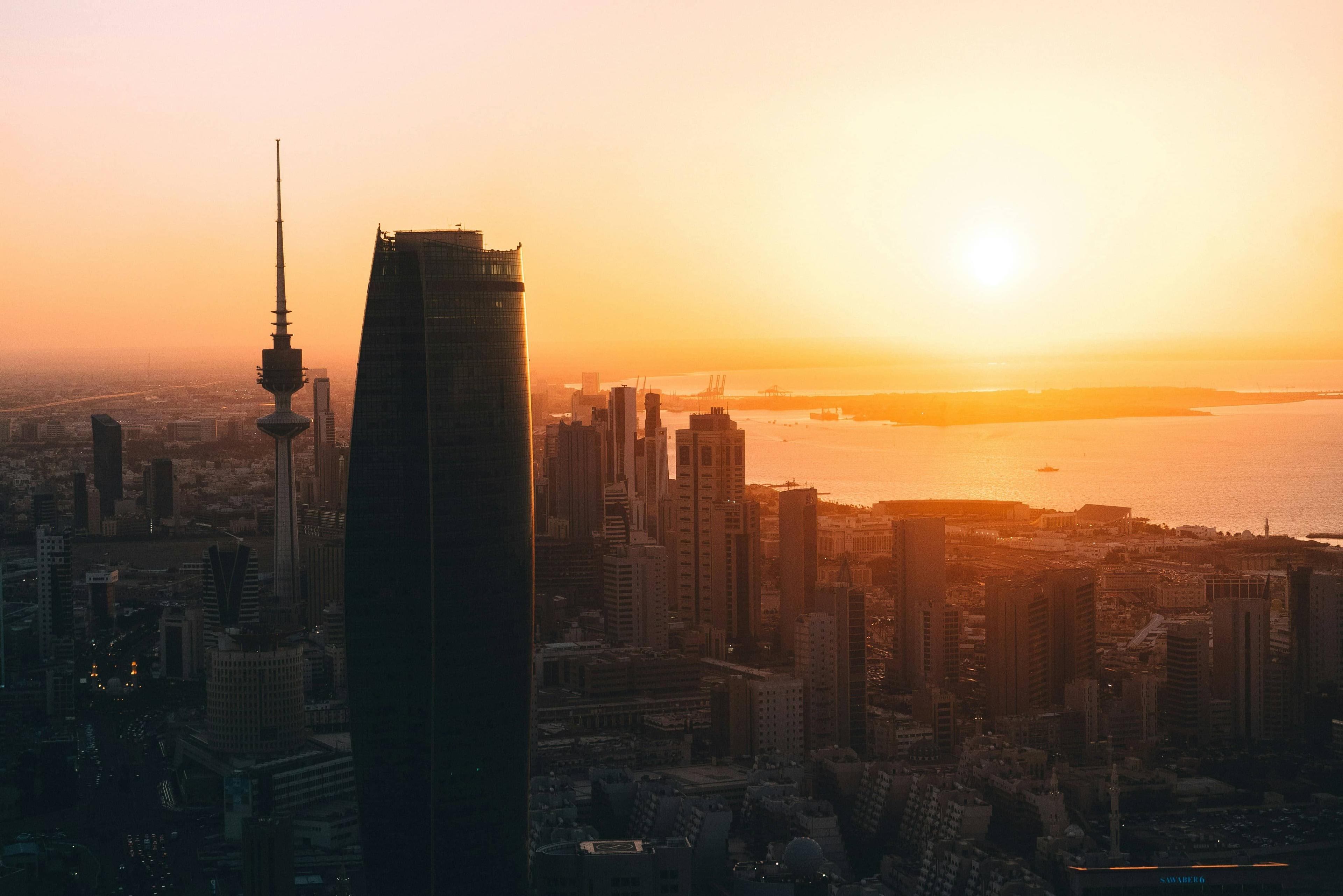 Vibrant orange sunset over a city skyline with tall buildings and a distinctive communication tower.