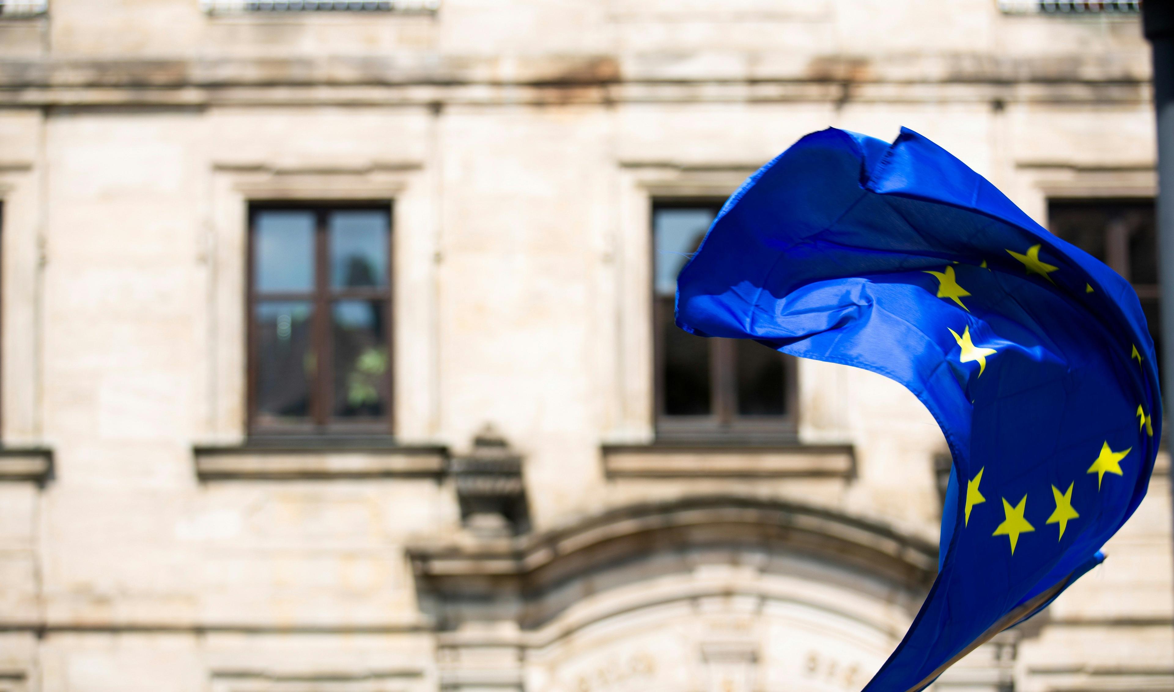 European Union flag waving proudly in front of a classical building.